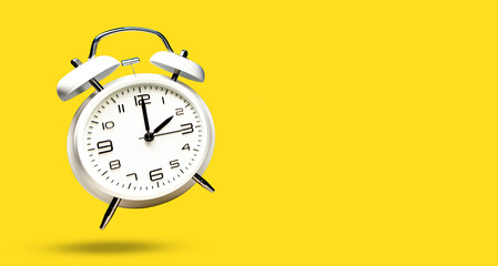 White bell alarm clock hovering over yellow background. 2 to 3 clock concept isolated. time change © ImageSine
