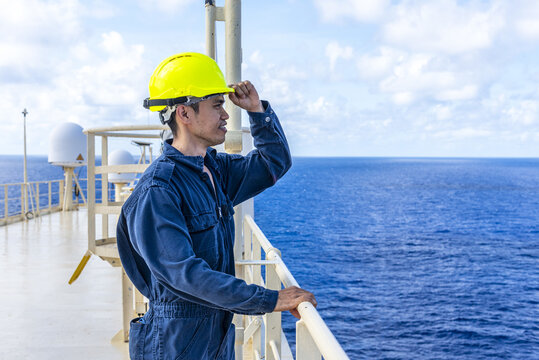 Seafarer from the engine department standing outdoors on cargo ship deck during sea passage.