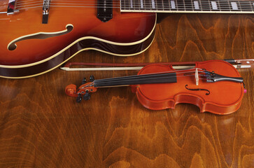Obraz premium Artistic attributes. Music. Electric guitar, violin with bow on wooden background.