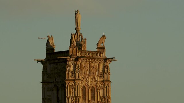 The Saint Jacques tower in Paris at sunrise  with a plane passing by in the background