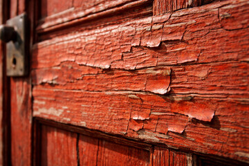 Close-up of weathered red wooden door with peeling paint