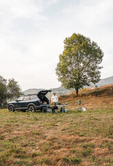 Young adventurer camping in the mountains with a blue car