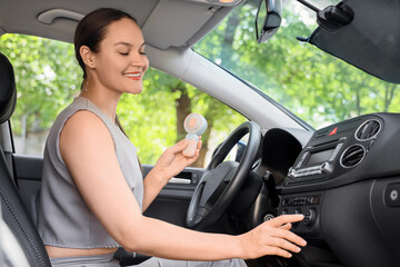 Naklejka premium Young woman using mini electric fan in car