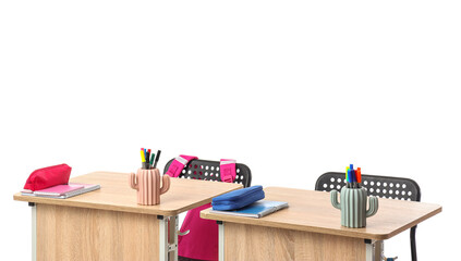 School desks with stationery and backpacks on white background