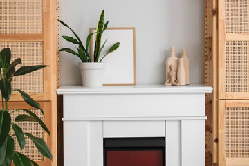 Naklejka premium Plant with frame and decor on fireplace in living room