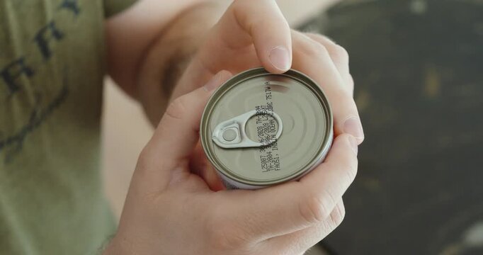 Close-up of hands holding a canned food container and reading the printed expiration date on the lid, highlighting food safety, shelf life, and responsible consumption.