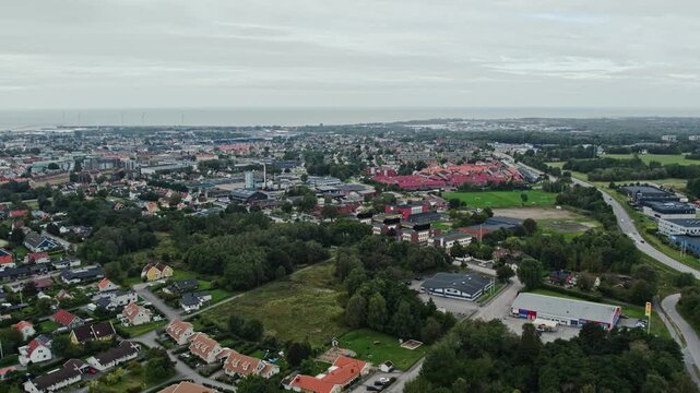 Drone view over Falkenberg in Sweden with residential areas, urban districts and the west coast visible on the horizon. Aerial view of Scandinavian coastal city landscape from above.