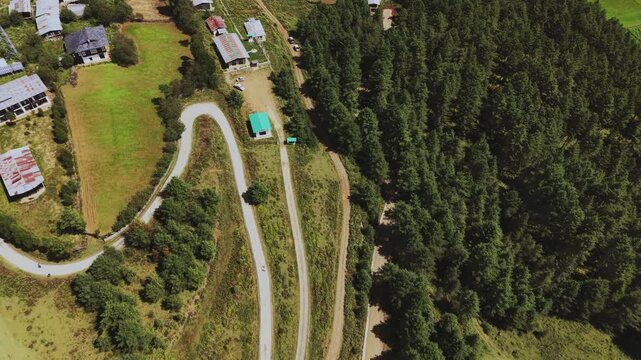 Nubding, Bhutan - 21 September 2025: Aerial view of a winding road cutting through the vibrant landscape, contrasting with the dense forest and scattered houses.