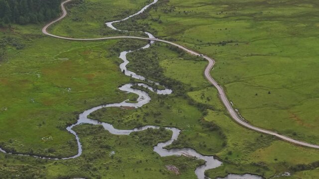 Aerial view of the Phobjikha Valley featuring a winding road and river cutting through the vibrant green landscape, Nubding, Bhutan.