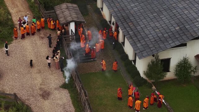 Nubding, Bhutan - 21 September 2025: Aerial view of monks in orange robes gathered at Phobjikha Valley, creating a vibrant contrast against the buildings.