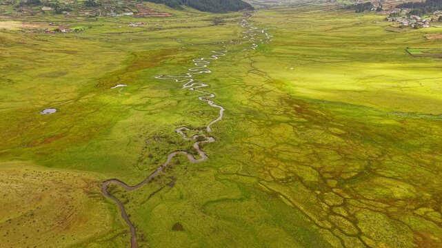 Aerial view of the winding river through the lush green Phobjikha Valley, its curves creating a mesmerizing pattern across the landscape, Nubding, Bhutan.