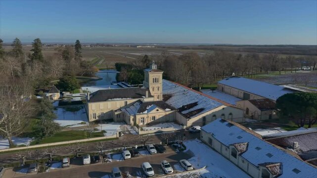 Chateau Lagrange, France - 06 January 2026: Aerial view of Chateau Lagrange Est under snow, contrasting the white roofs with the green lawns and the dark water pond.