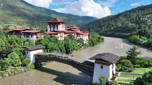 Aerial view of Punakha Dzong, a fortress monastery with vibrant red roofs and white walls, nestled by a winding river amid lush green hills, Punakha, Punakha, Bhutan.