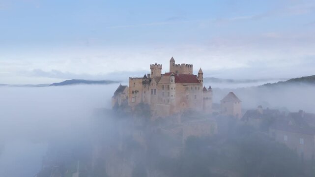Beynac-et-Cazenac, France - 12 September 2025: Aerial view of the Chateau de Beynac emerging from a sea of fog, a medieval fortress standing proudly above the mist.