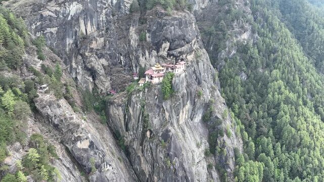 Aerial view of Tiger's Nest Temple perched on a cliff, a striking contrast against the rugged terrain and lush greenery, Taktsang, Paro, Bhutan.