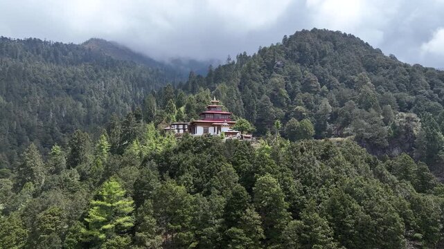 Aerial view of the Tiger's Nest temple perched high on a cliff, surrounded by lush forests and mist-covered mountains, Taktsang, Paro, Bhutan.