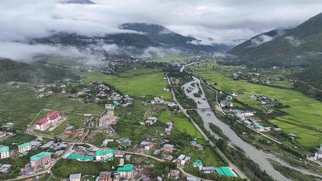 Aerial view of a winding river cutting through the lush green valley, nestled among rolling hills in the serene landscape, Paro, Bhutan.