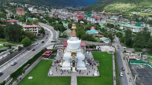 Aerial view of the National Memorial Chorten, a striking white and gold structure surrounded by lush green lawns and bustling city streets, Thimphu, Bhutan.