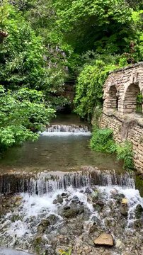 View of a small waterfall in rocks among trees and greenery in Balchik, Bulgaria. 4k