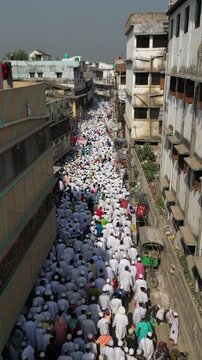 Aerial view of people congregating on the street amid buildings, a sea of white contrasts against the old, weathered architecture, Malda, West Bengal, India.
