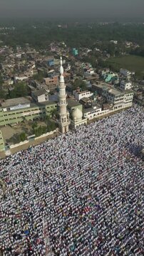 Aerial view of a large crowd gathered near a mosque, the white attire of the people contrasting with the surrounding buildings, Malda, West Bengal, India.