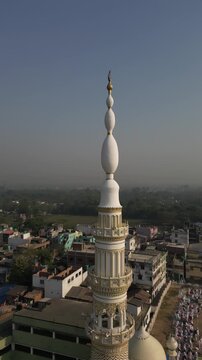 Aerial view of a tall mosque minaret rising high above the city, its intricate designs standing out against the muted skyline, Malda, West Bengal, India.
