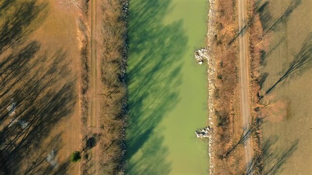Aerial view of the Drau River cutting through the landscape, casting long shadows across the fields, Drautal, Carinthia, Austria.