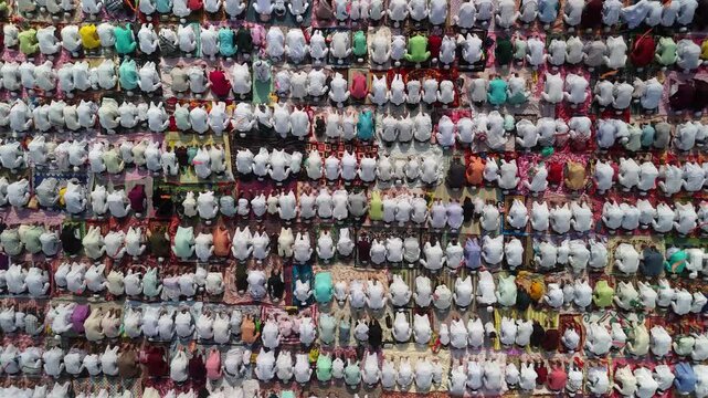 Aerial view of worshippers in rows, a sea of white punctuated by vibrant colors, showing unity and devotion in prayer, Malda, West Bengal, India.