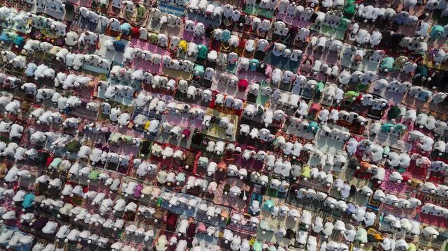 Aerial view of many people praying in congregation, their white and colorful clothing contrasting against the ground, Malda, West Bengal, India.