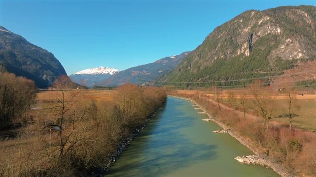 Aerial view of the Drau river flowing through the valley between mountains, with patches of snow on the mountain peaks, Greifenburg, Carinthia, Austria.