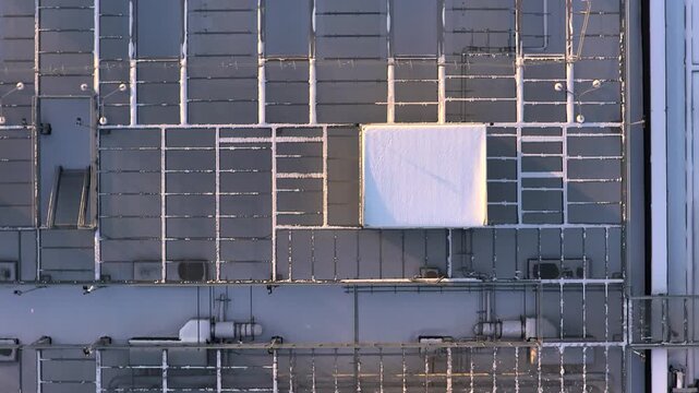 Aerial view flying over a modern data center rooftop with its complex cooling and ventilation systems covered in winter snow, Warszawa, Poland.