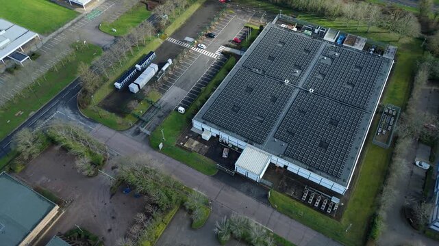 Aerial view of a large data centre contrasts with the solar panels adorning its roof and the surrounding greenery, Milton Keynes, United Kingdom.