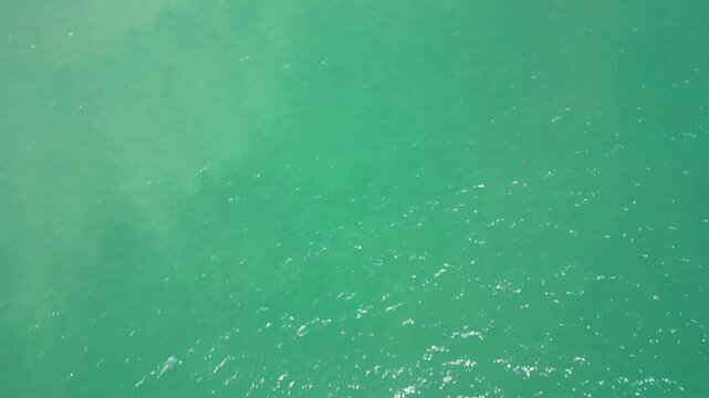 Aerial view of the turquoise ocean water rippling in the sunlight, creating a mesmerizing pattern of light and shadow, Lagoa, Faro District, Portugal.