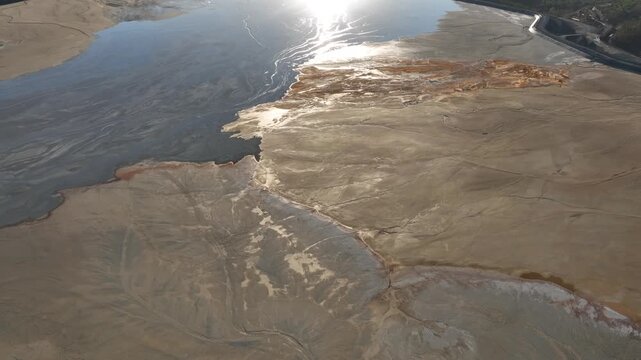 Aerial view of a barren landscape, showcasing the stark contrast between the muted earth tones and the dark waters, Minas de Riotinto, Andalusia, Spain.