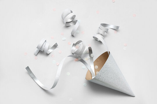 Silver party hat with serpentine and confetti on grey background
