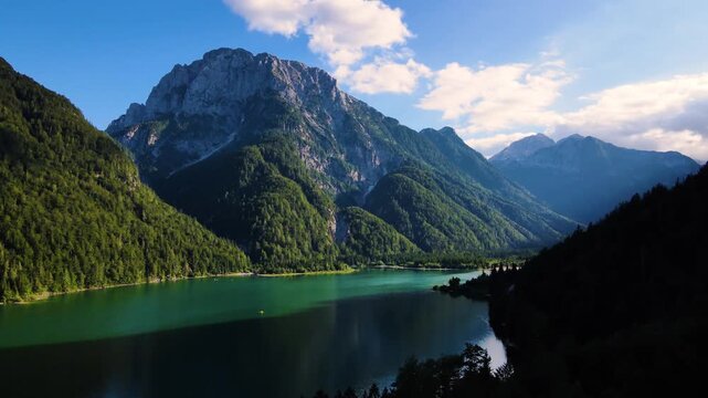Aerial view of the stunning Lake Predil, its turquoise waters reflecting the towering mountains covered in lush greenery, Friuli-Venezia Giulia, Italy.