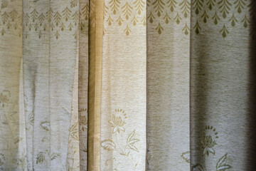 closeup view of beige fabric curtain with subtle floral pattern and soft indoor lighting texture background
