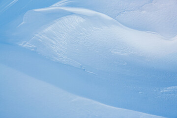Beautiful winter background with snowy ground. Natural snow texture. Wind sculpted patterns on snow surface.