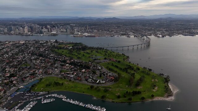 Aerial view of the Coronado Bridge stretching across the bay with a city skyline in the distance under a cloudy sky, Coronado, California, United States.