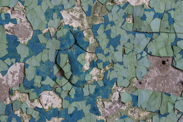 Peeling paint on the wall. Old concrete wall with cracked flaking paint. Weathered rough painted surface with patterns of cracks and peeling. Grunge texture for background and design. High resolution.