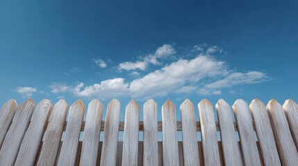 White Wooden Picket Fence Against Bright Blue Sky with Soft Clouds in the Background for Outdoor Aesthetic and Design
