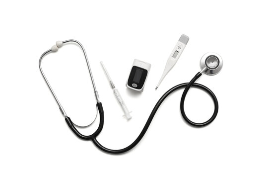 Pulse oximeter, stethoscope, thermometer and syringe on white background