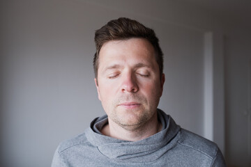 Fototapeta premium Serene middle aged Caucasian man standing with closed eyes, enjoying a peaceful moment 