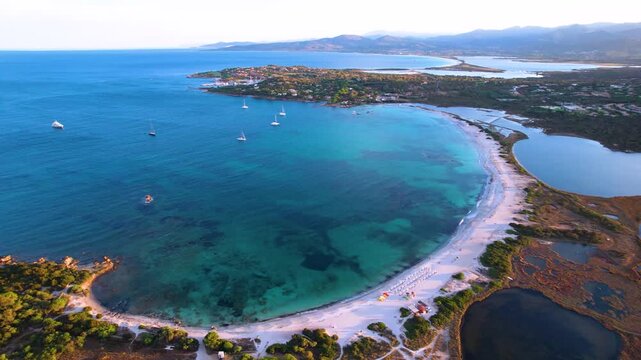 Sardinia Lu Impostu sunset 4K drone. Dark salt lake and round bay beach contrast. Aerial golden hour Sardegna. Mediterranean evening travel. San Teodoro coastline
