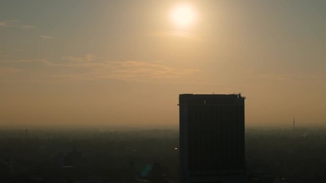 4K hazy urban landscape showing a modern skyscraper in a foggy tropical city at dawn