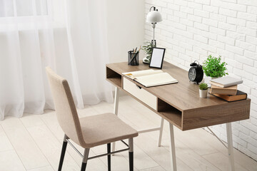 Fototapeta premium Stylish desk, lamp, notebook and chair in light room