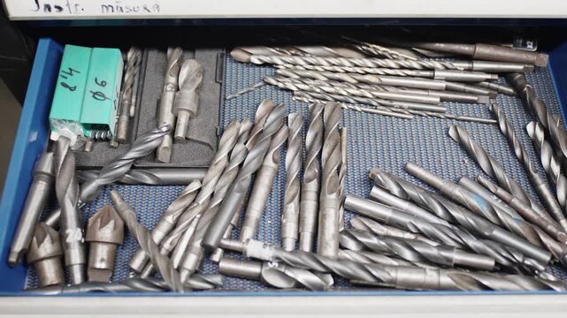 Shot over a blue workshop drawer filled with various metal drill bits
