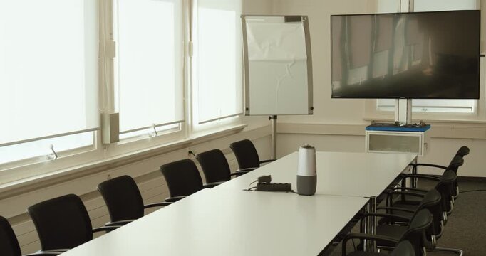 Bright and modern meeting room with long table, chairs, flip chart, and large display screen, prepared for a business conference, workshop, or corporate training session.
