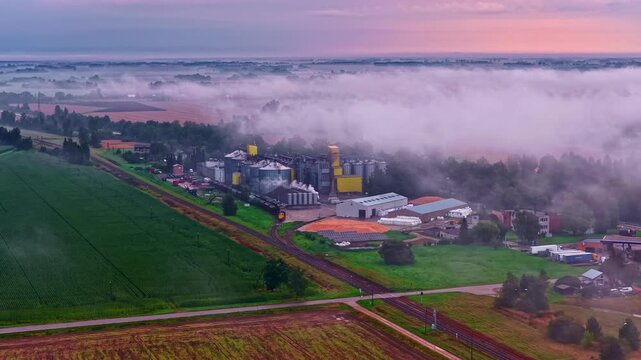 Aerial: plant with cloudy sky, forest and fields around during the day, outdoor, establishing drone shot
