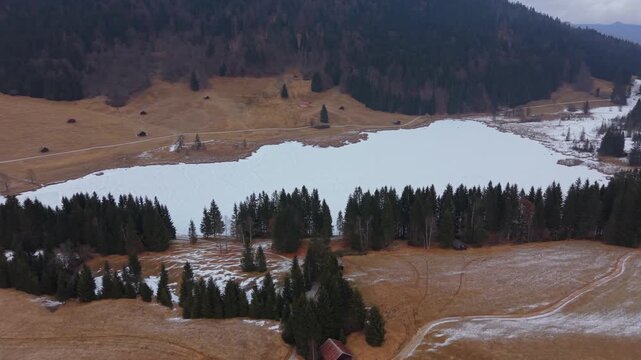 Drone view of the snowy Wagenbruchsee in the Kruen region. A famous alpine lake destination in Bavaria. Perfect winter footage of the Geroldsee under a cloudy winter sky.